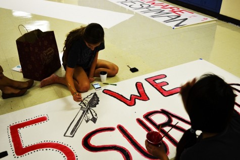 Victoria Hanley paints the "1-5 We Survived" banner.