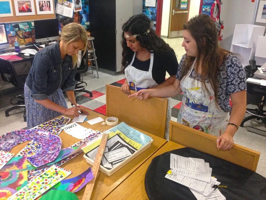 Art students Grace Almanza and Adison Gonzalez help photography teacher Ms. Ardner with preparation for the upcoming art show.