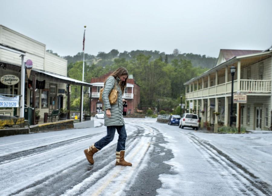 Wine shop owner Susan Feist leaves her store, Feist Wines in Amador City, Calif., on Tuesday, April 7, 2015, as hail falls during a severe storm that fell in the region. (Hector Amezcua/Sacramento Bee/TNS)