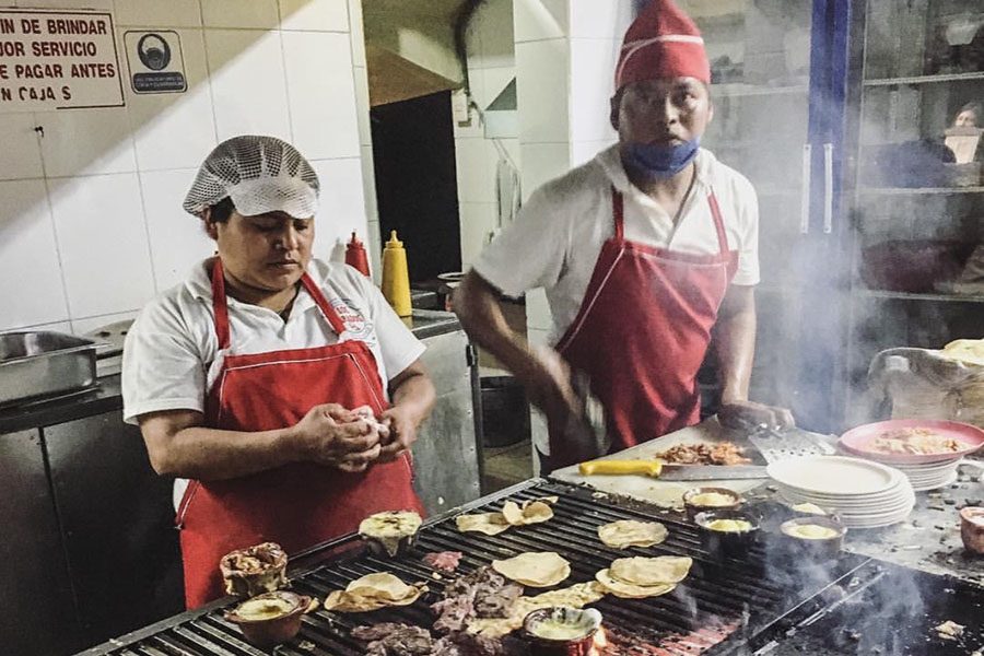 Two staff members cooking tacos.
