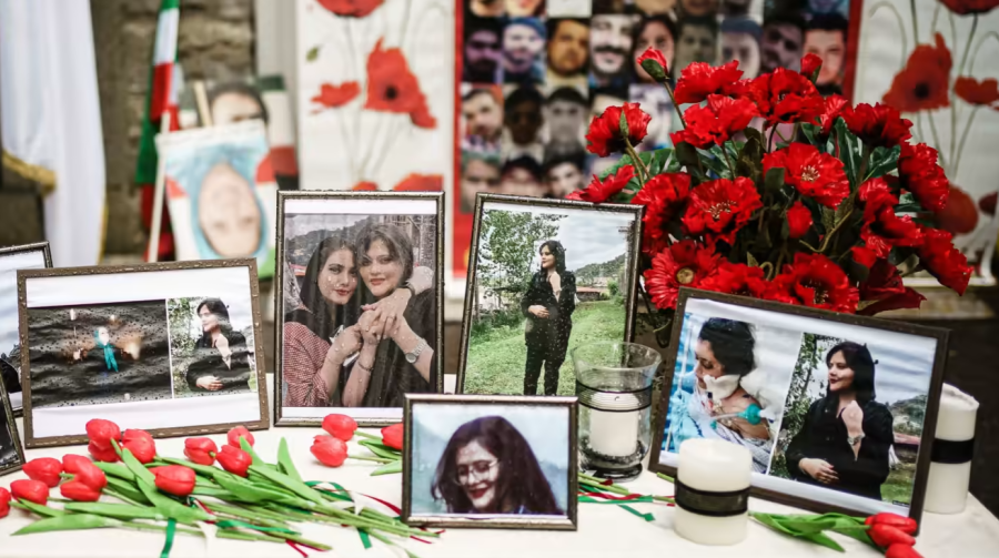 A table of flowers and pictures of Mahsa Amini in honor of her