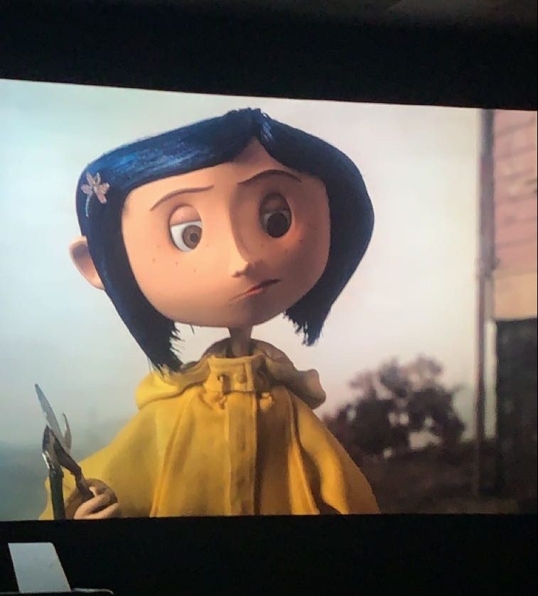Coraline with her infamous yellow coat on the theater screen.