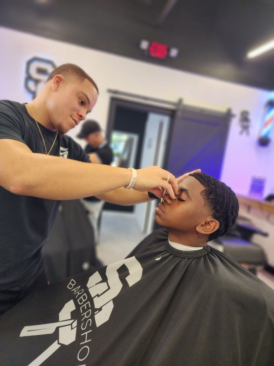 Photo of Damion Nosistel at Sir Cutz Barbershop getting a taper fade. 
