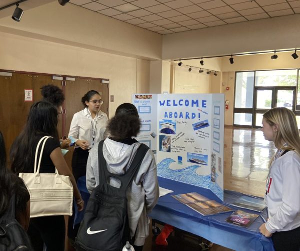 Students presenting a poster board about cruise ships to visitors