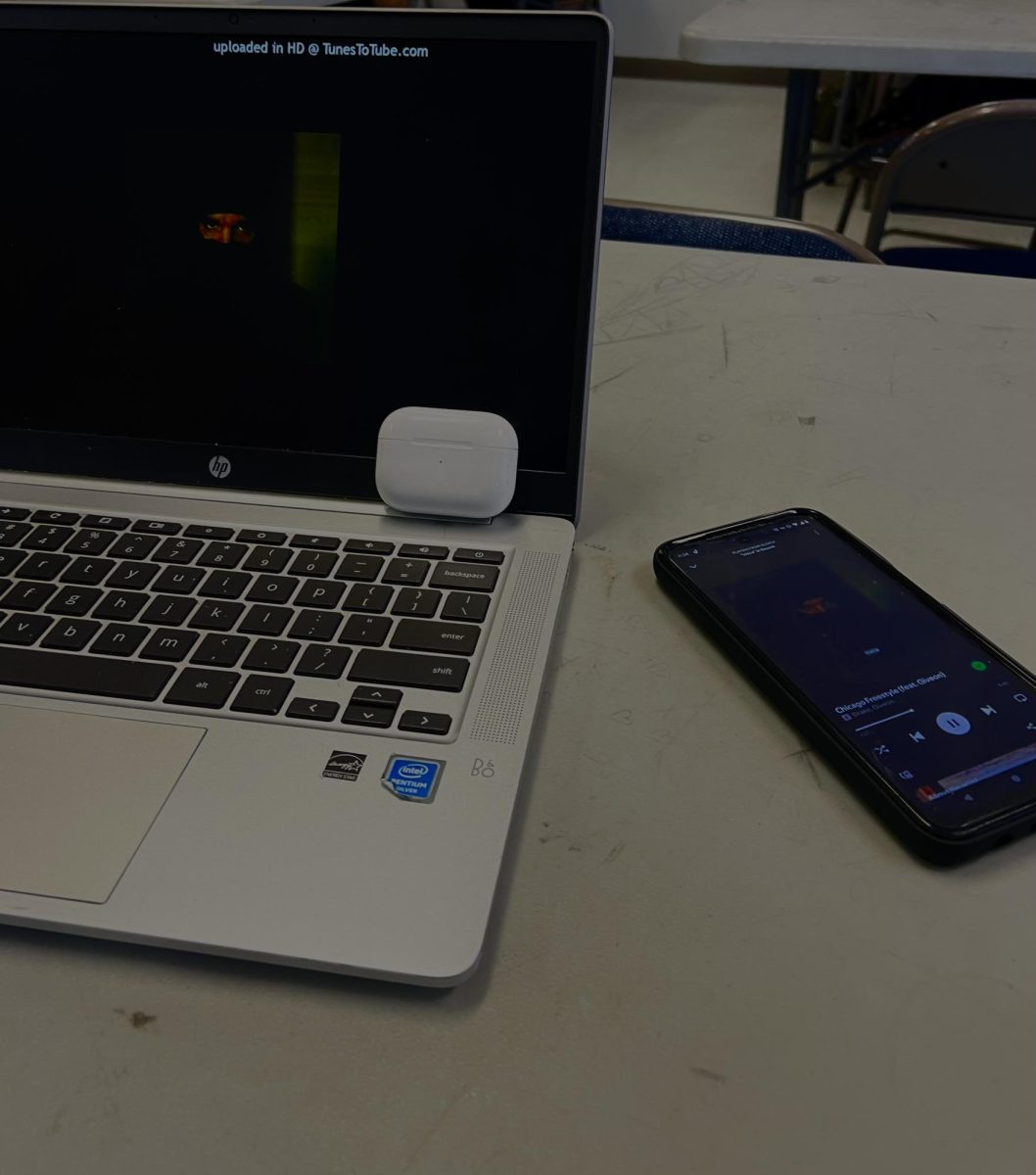 A phone with music playing beside a laptop.