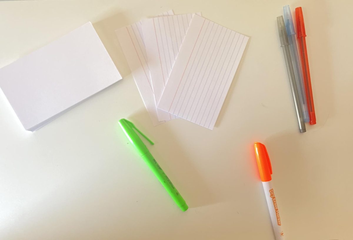Index cards, highlighters, and pens laid out on a table to use for studying.